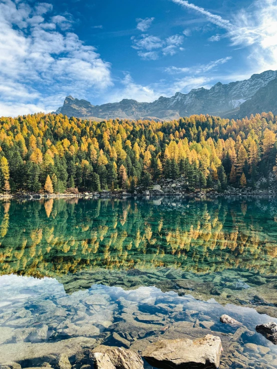 a lake surrounded by mountains with rocks and grass in it