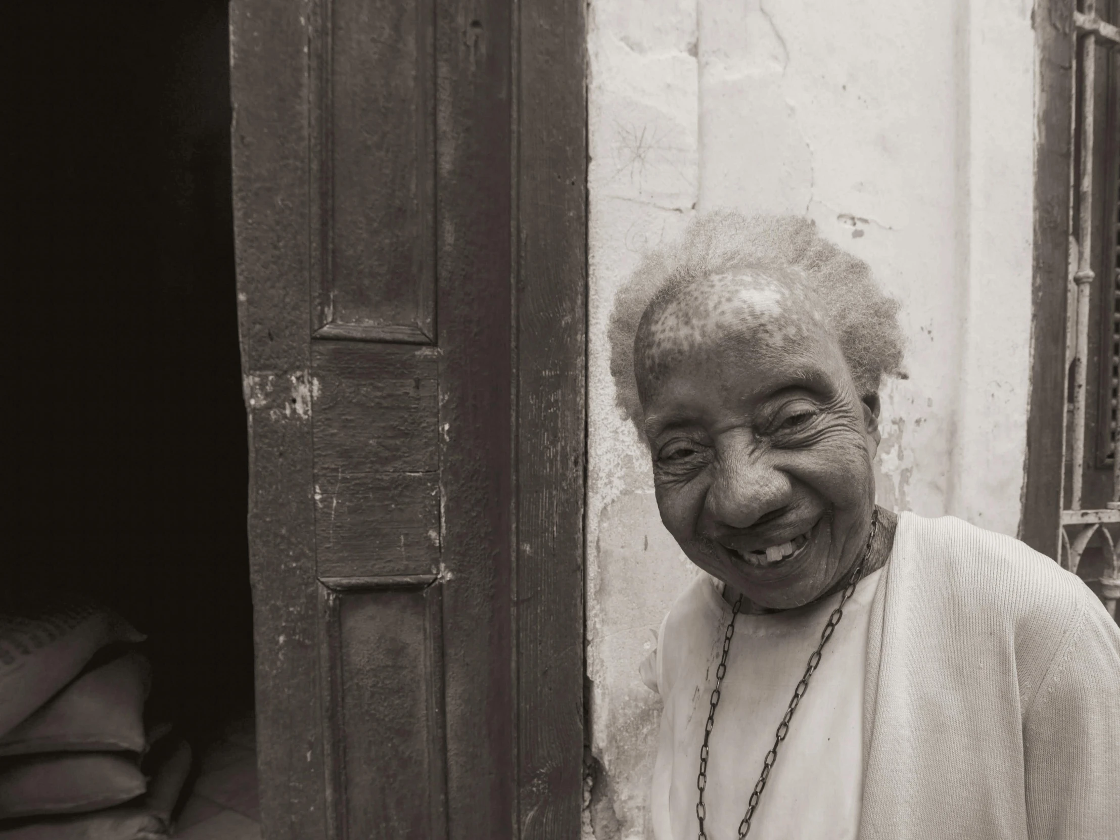 an old woman with a beaded necklace standing next to a building