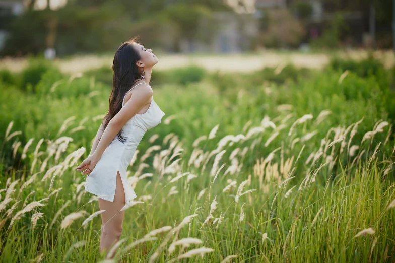 woman in white dress standing among tall grass