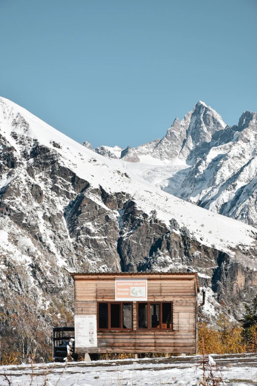 a small wooden structure with a sign on it is surrounded by mountains