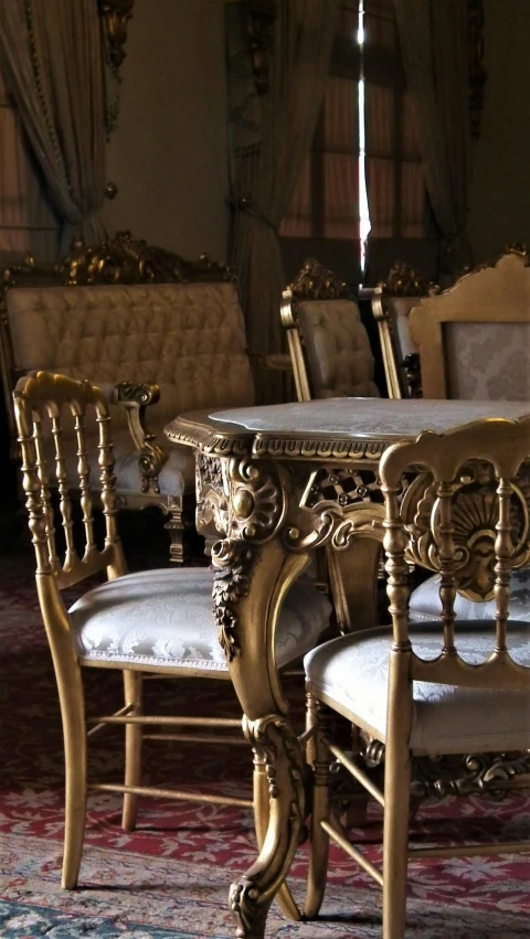 a set of chairs with arms, and a table covered in an elaborately carved wooden tablecloth