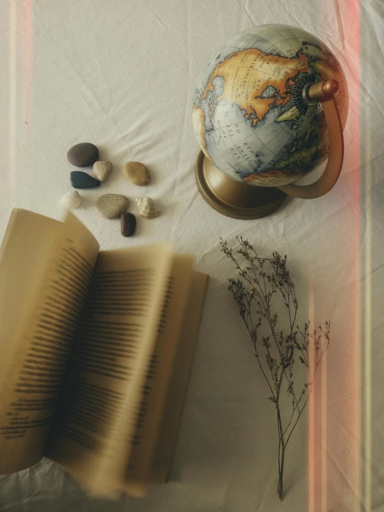 an open book, a flower and rocks on a blanket