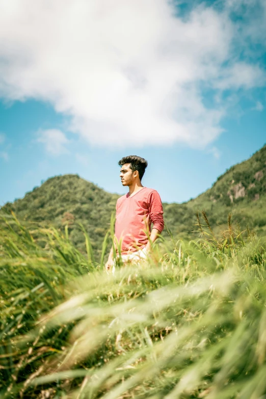 man standing in grassy area near mountains under clouds