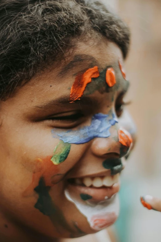 a smiling little girl with her face paint all over her