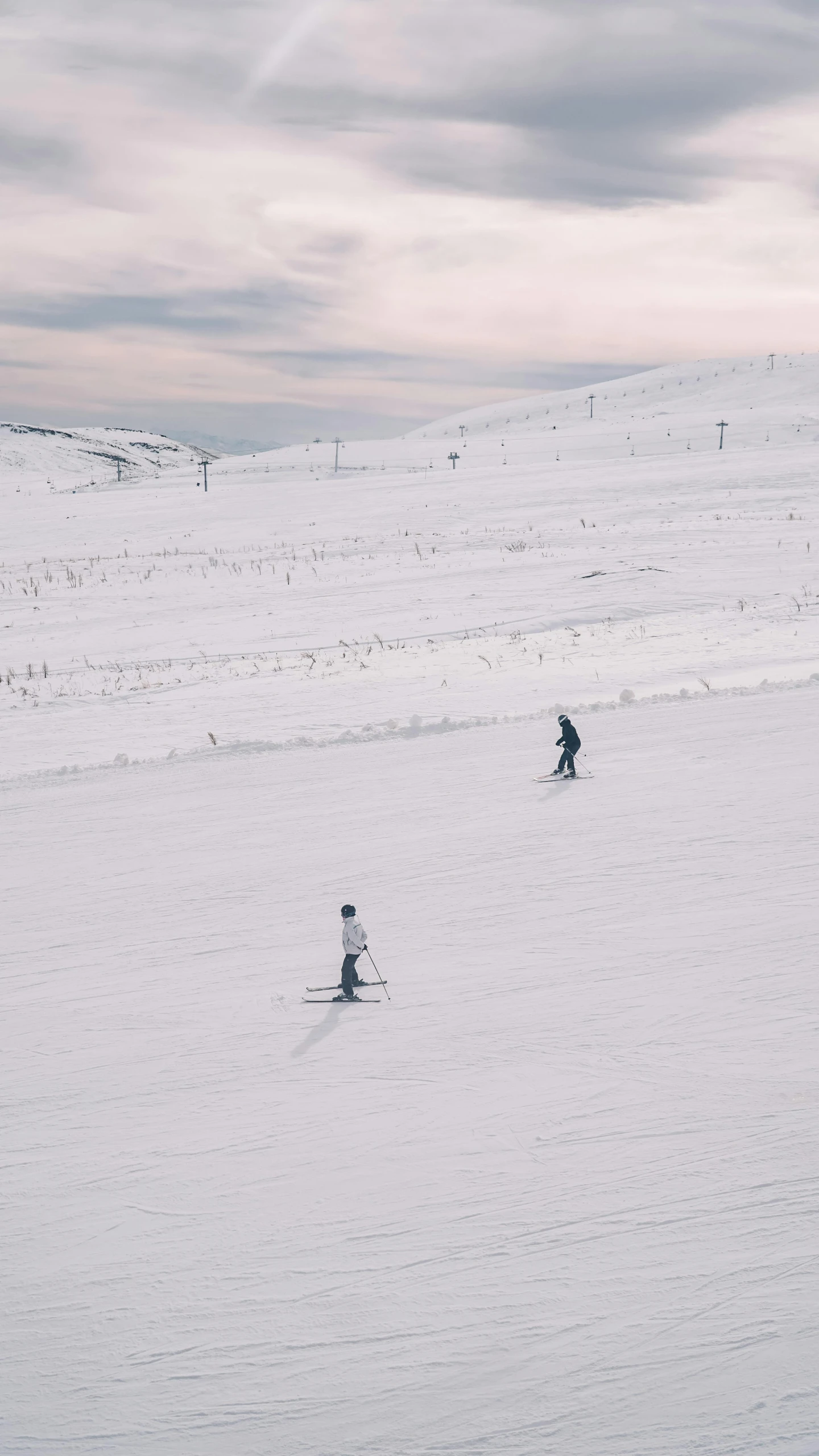 two people skiing on the snow with one going up hill