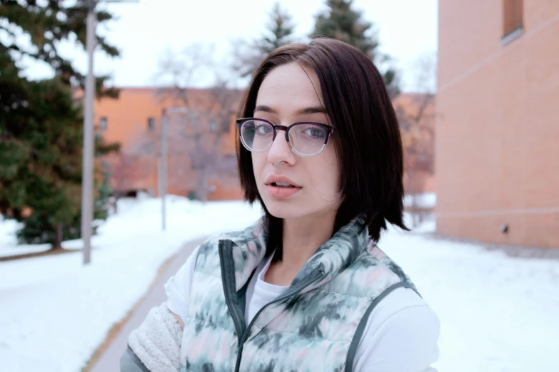 woman in glasses posing on a snowy city street