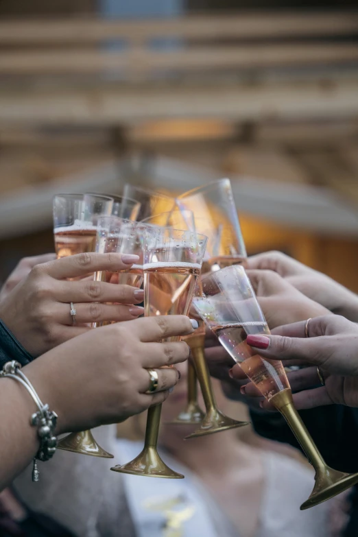 some people are holding wine glasses with different amounts