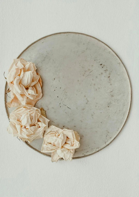 large plate with rolled flowers on a white wall