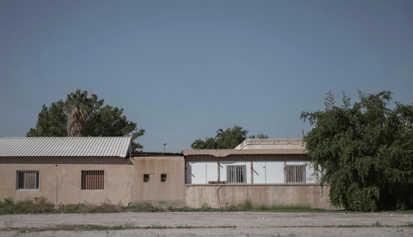 a building sitting next to some trees on a dirt road