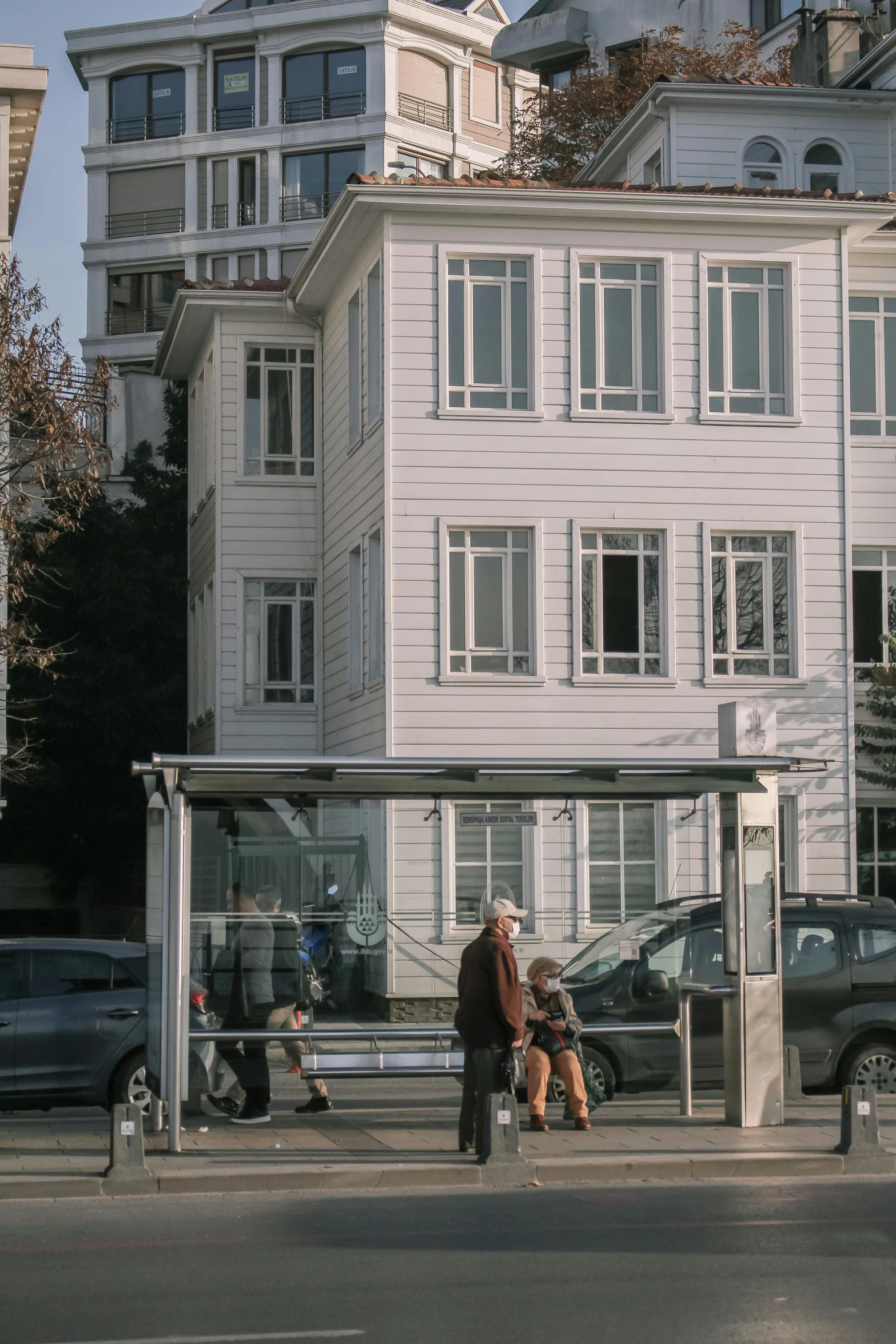 a couple sitting on a bench near a bus stop