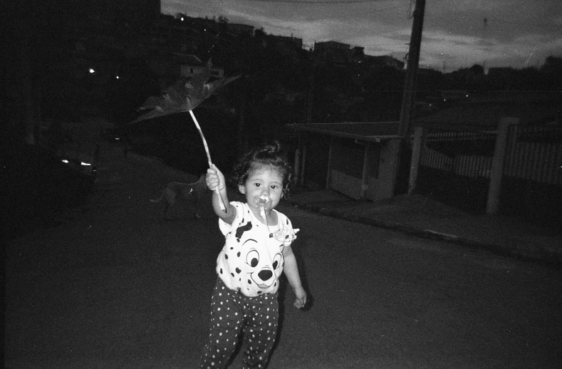 a child holding an umbrella on a street at night