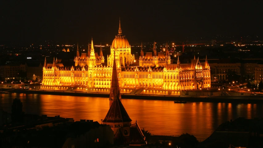 large building lit up in front of a body of water