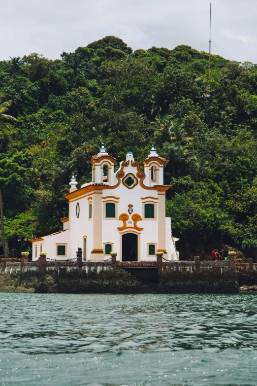a church on the water in front of a cliff
