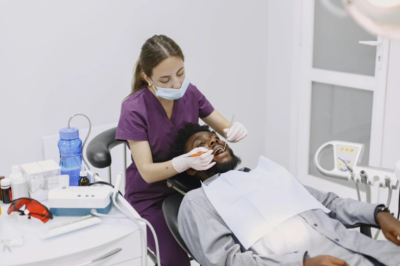 a female doctor examines a man in the dental chair