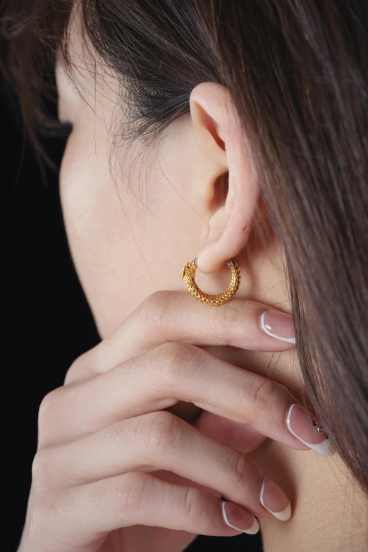 woman with hand holding on to ear wearing earrings