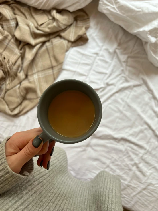 the woman is holding a cup of tea in her hand