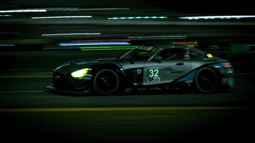 a grey car driving down a race track