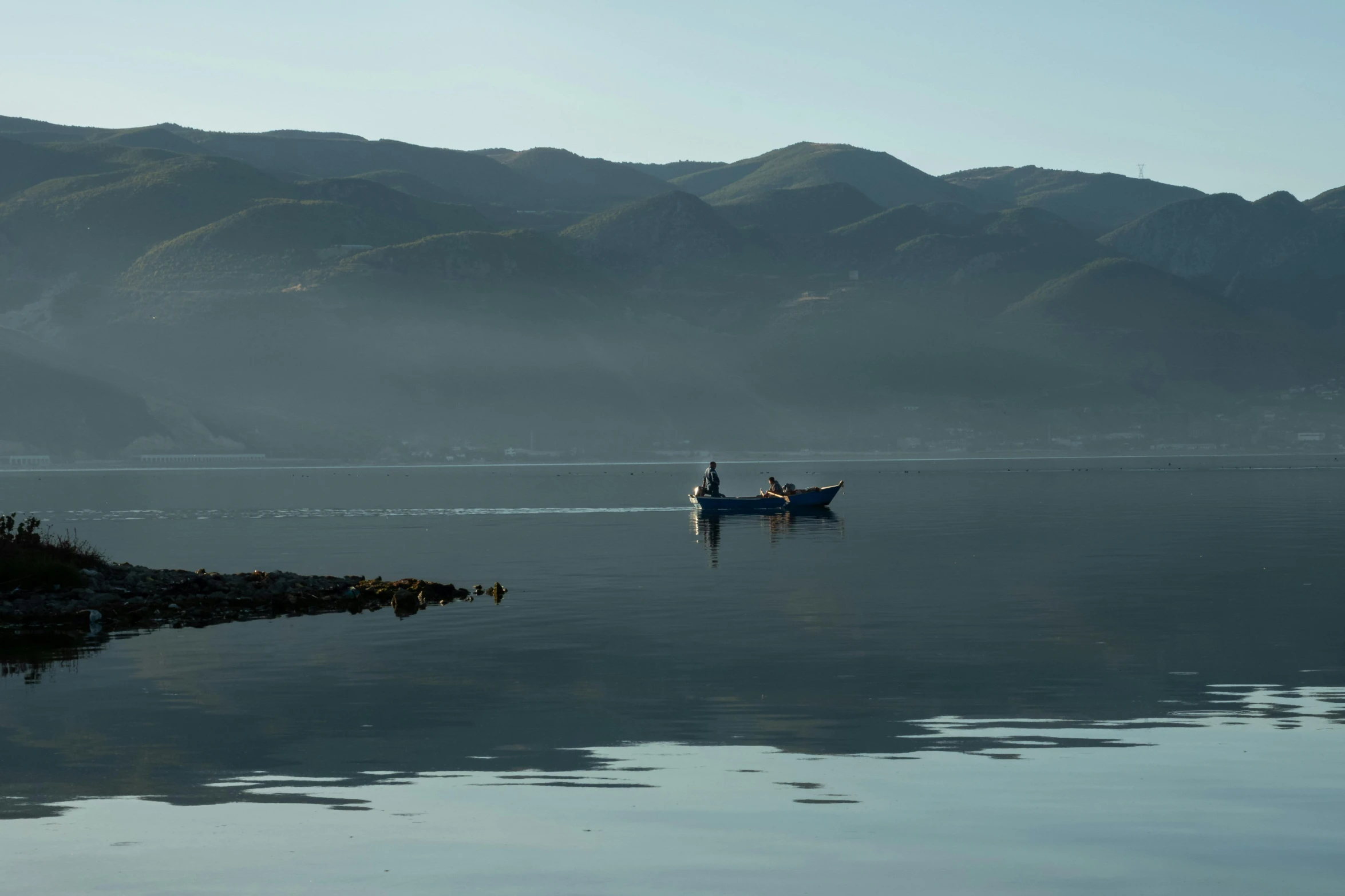 the sky is reflecting off the water, and a boat floats down