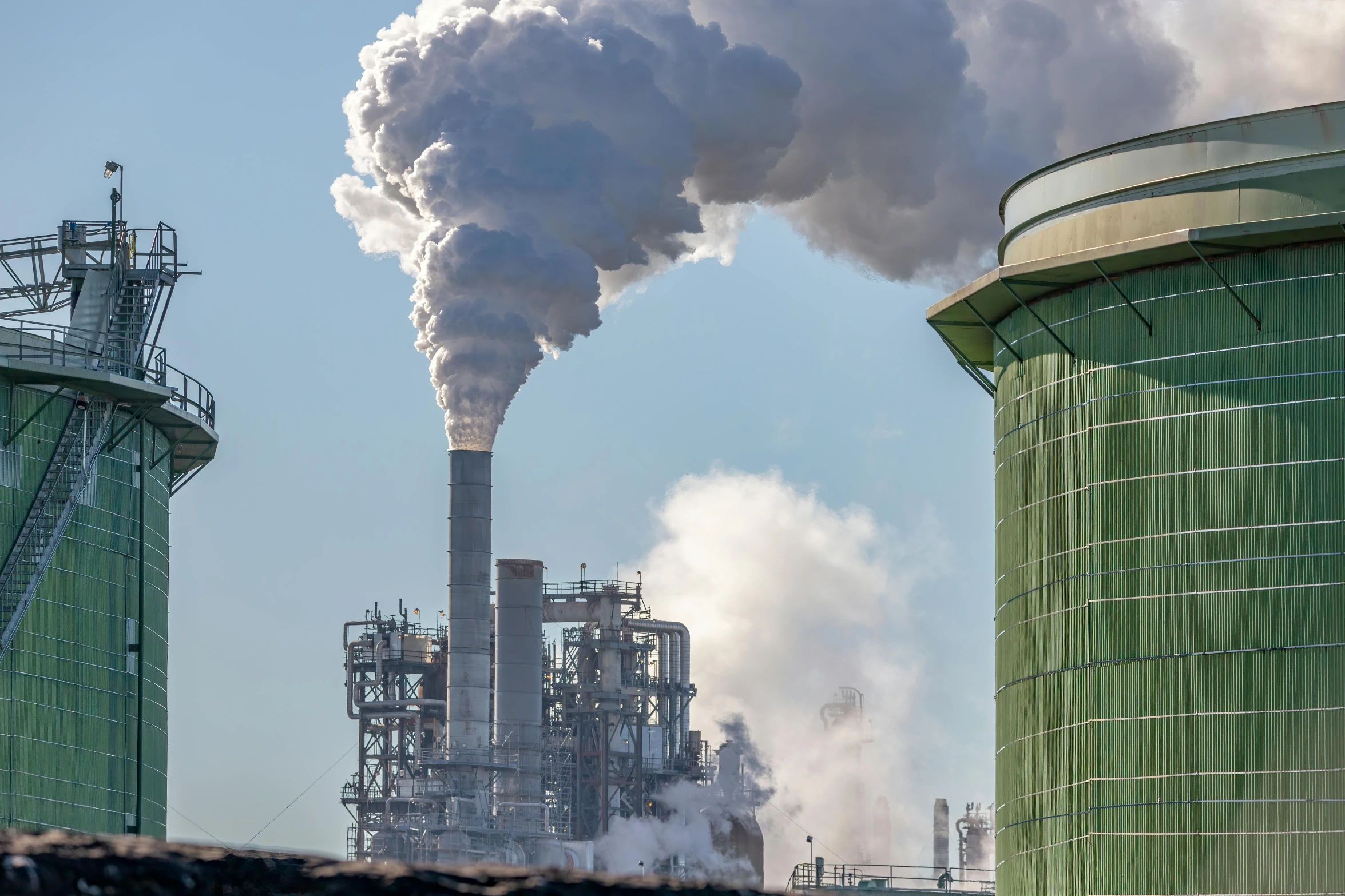 smoke billows from the stacks of industrial buildings