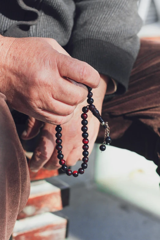 an older man holding a rosary necklace on the chest