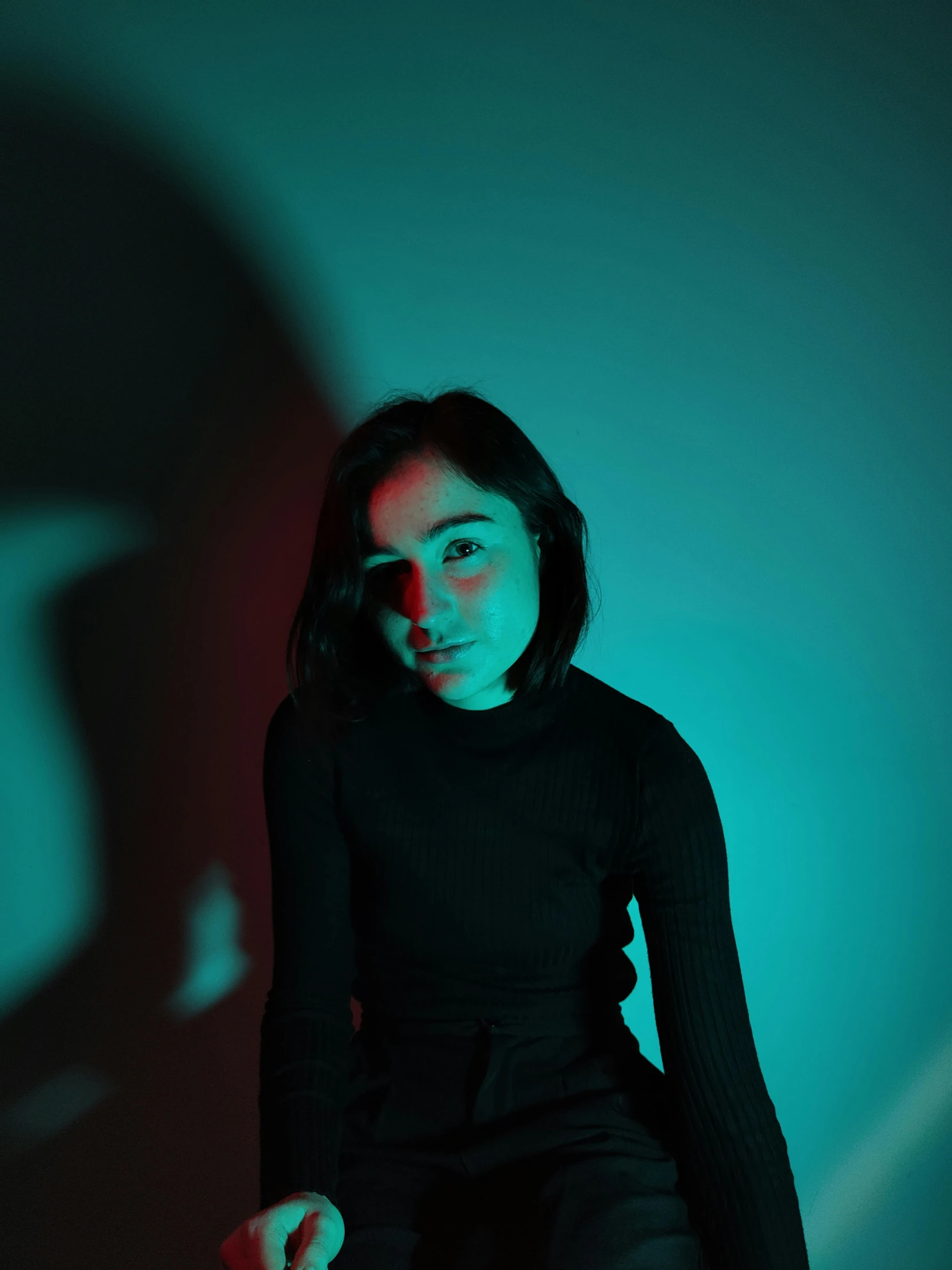 woman with long hair posing for a picture in a blue - green studio