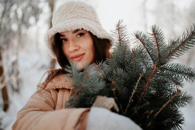 a beautiful young woman holding a pine tree