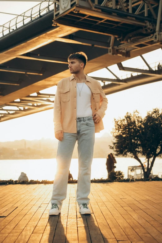 a man standing on the boardwalk with a bridge in the background