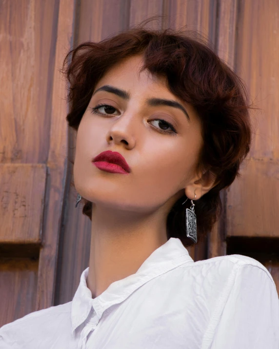 a woman with large earrings in front of a wall