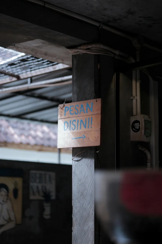 a wood sign on a metal pole saying persan disini