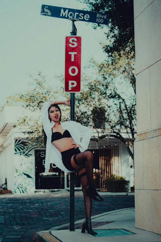 a woman is in lingerie holding onto a stop sign