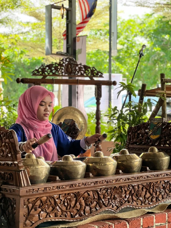 a woman in hijab standing behind a display of vases