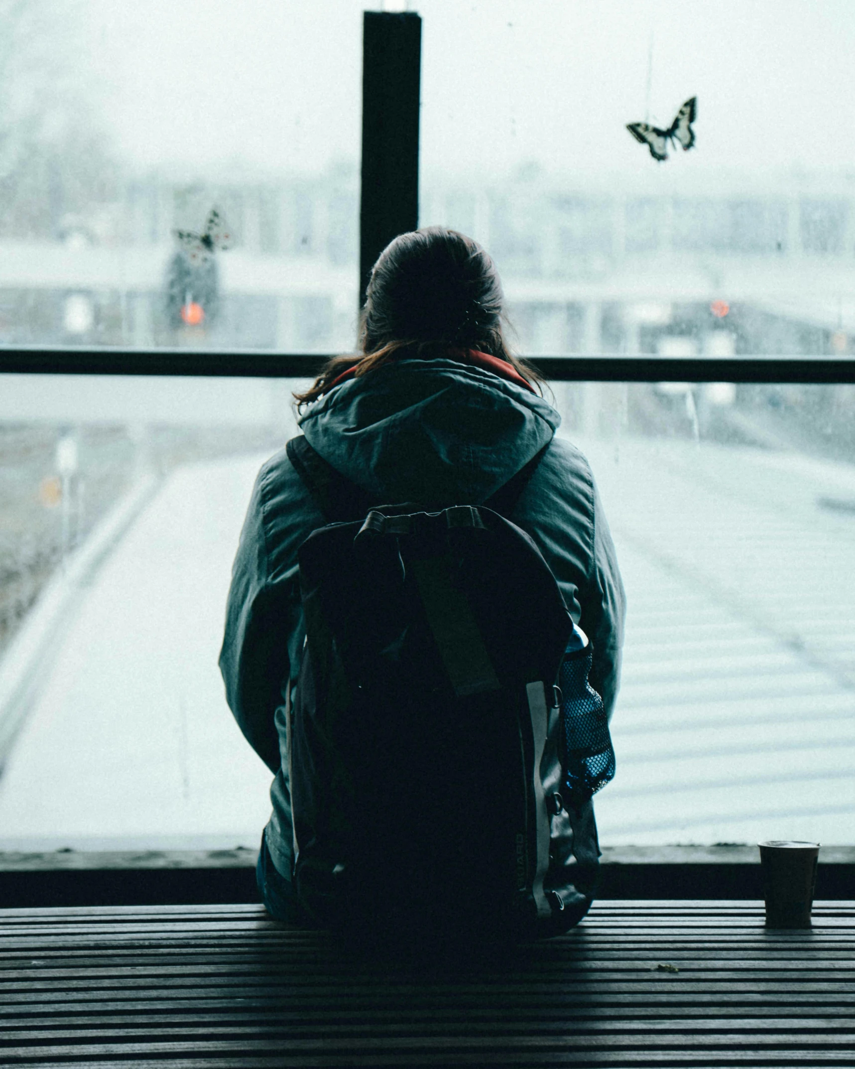 a person sitting on top of a bench next to a window