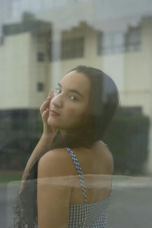 a woman looking out of a window with a building in the background