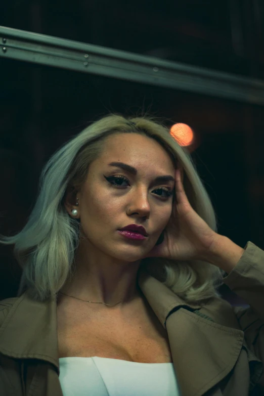 a woman with blonde hair stands in front of a window