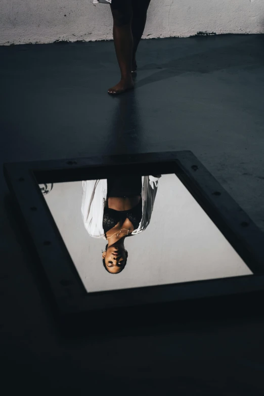 a person standing in a window with their reflection in the ground