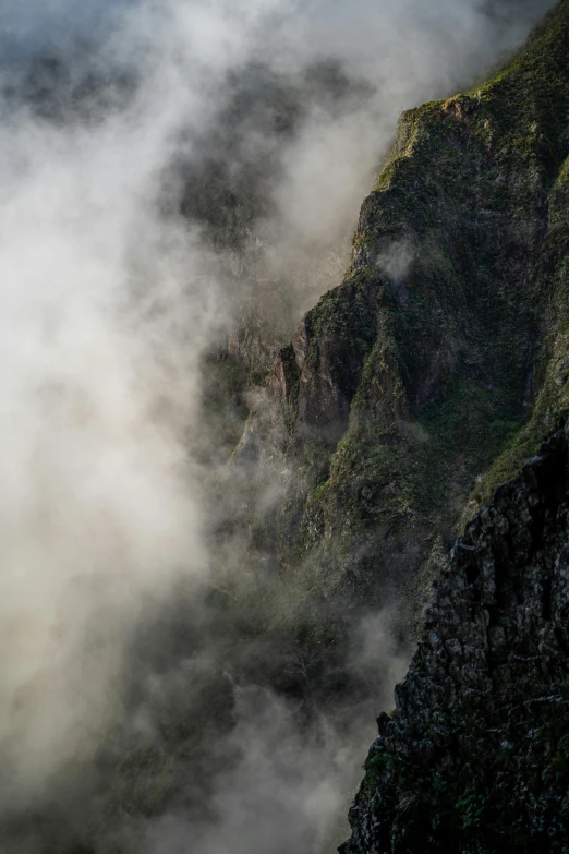 a large mountain with fog covered ground next to it