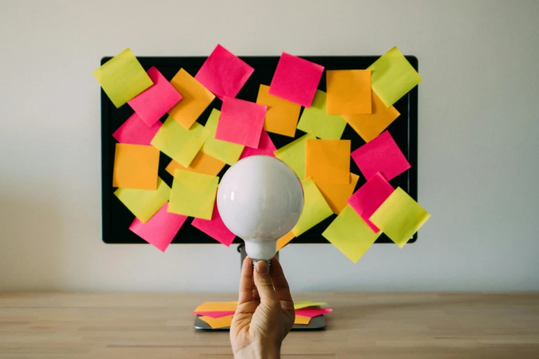 a man holds a blowdryer in front of colored sticky notes