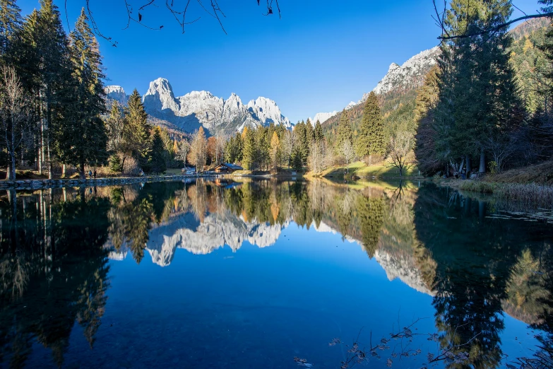 a lake surrounded by trees and mountains is clear