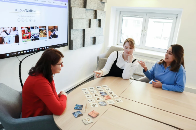 three people playing cards at a meeting table