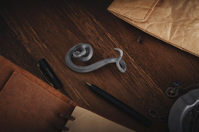 a desk with some pen, wallet, scissors, and a chain