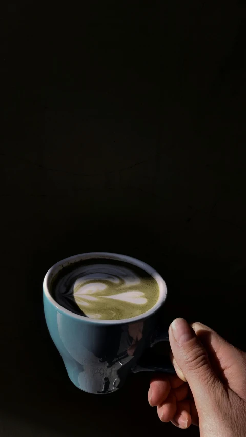 a coffee cup filled with green liquid in a black cup