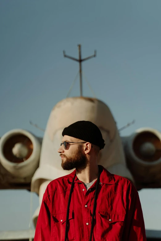 a man with glasses in front of an airplane