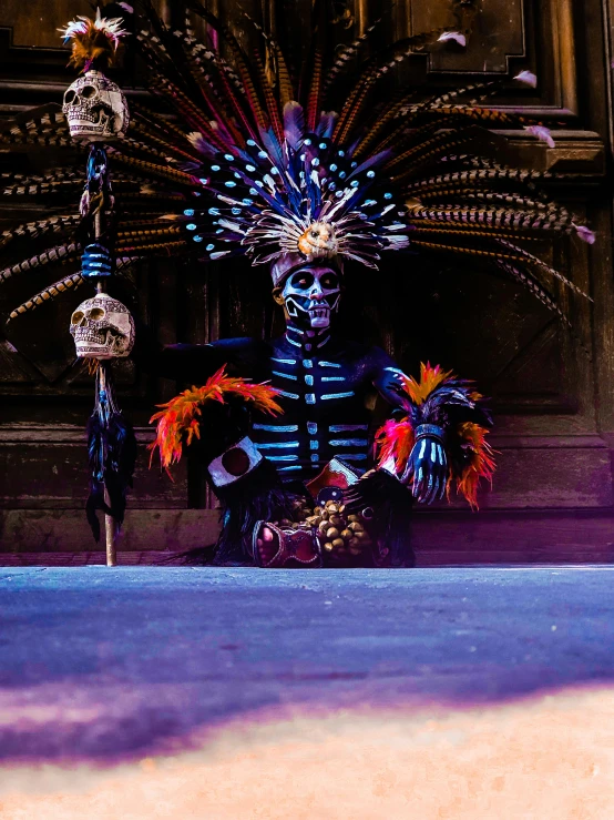 a masked performer is sitting outside on a sidewalk