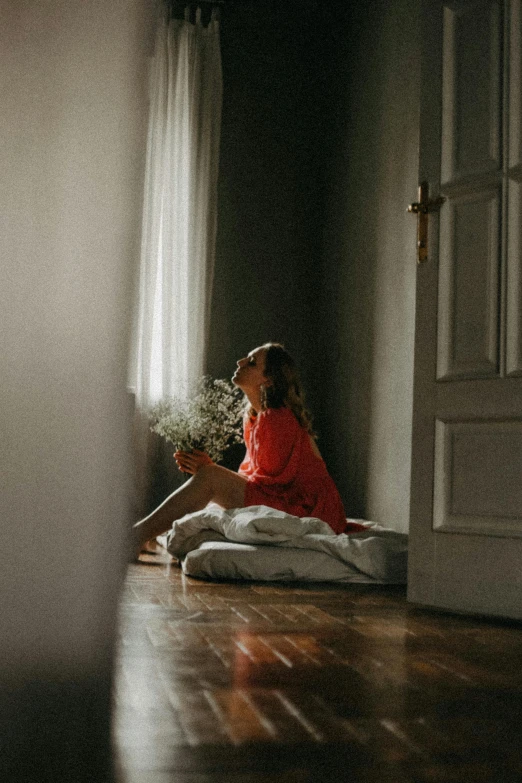 a  sitting on a floor holding flowers in her hand