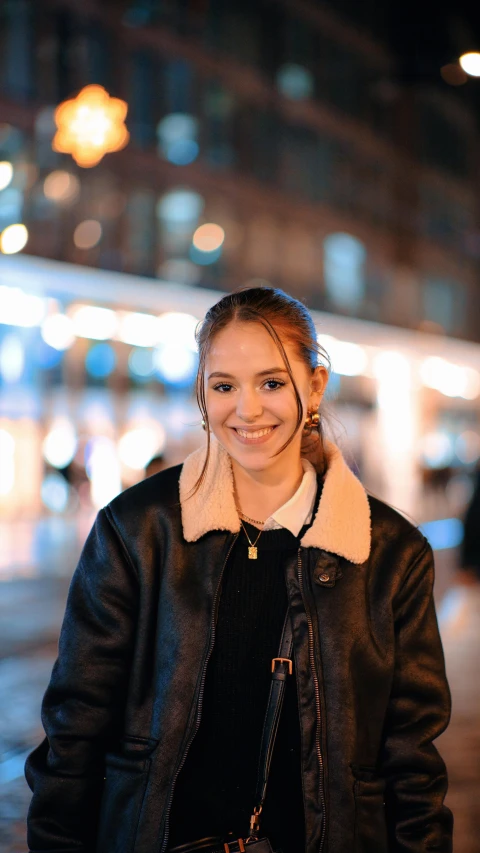 woman in leather jacket standing on street next to buildings