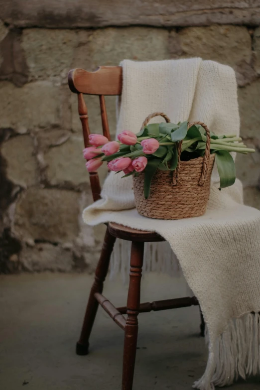 a basket with some pink flowers on a chair