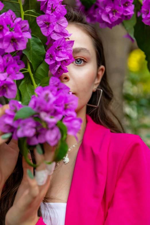 a woman in a pink jacket hiding behind flowers