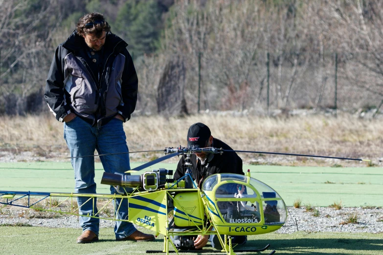 a man is looking at a yellow helicopter