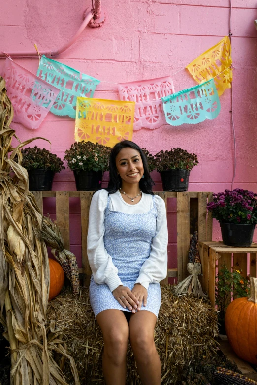 a woman is sitting on a wooden bench next to a fence