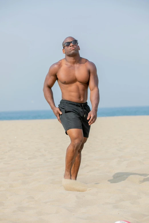 a man standing on the beach next to a soccer ball